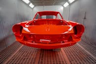 Vividly painted car body in a professional industrial spray paint booth.